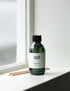 A 200ml bottle of lavender and linden essential oil diffuser refill by Land & Water, placed on a windowsill with reeds next to it.