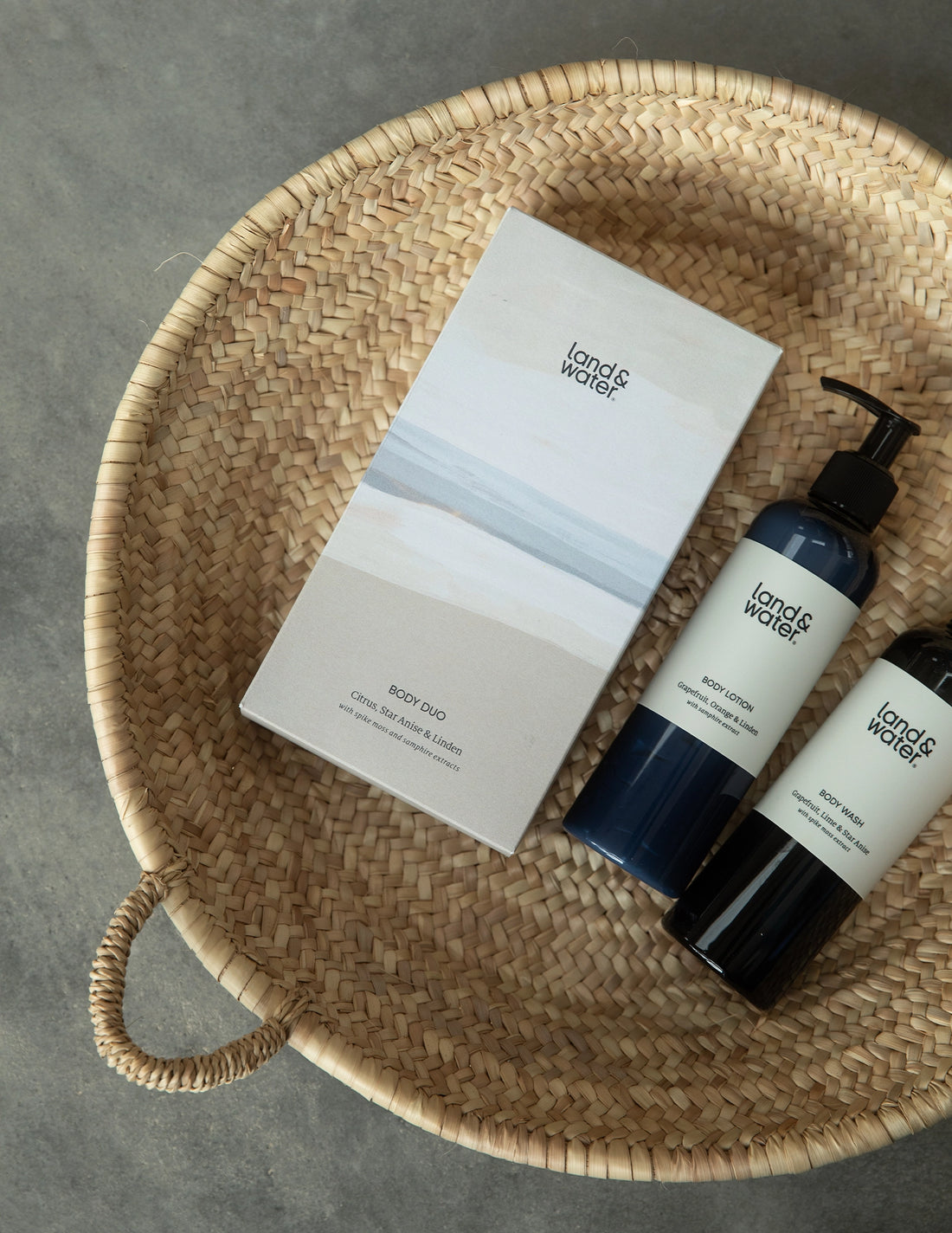 Body Wash bottle and Body Lotion bottle lying with gift box in a basket