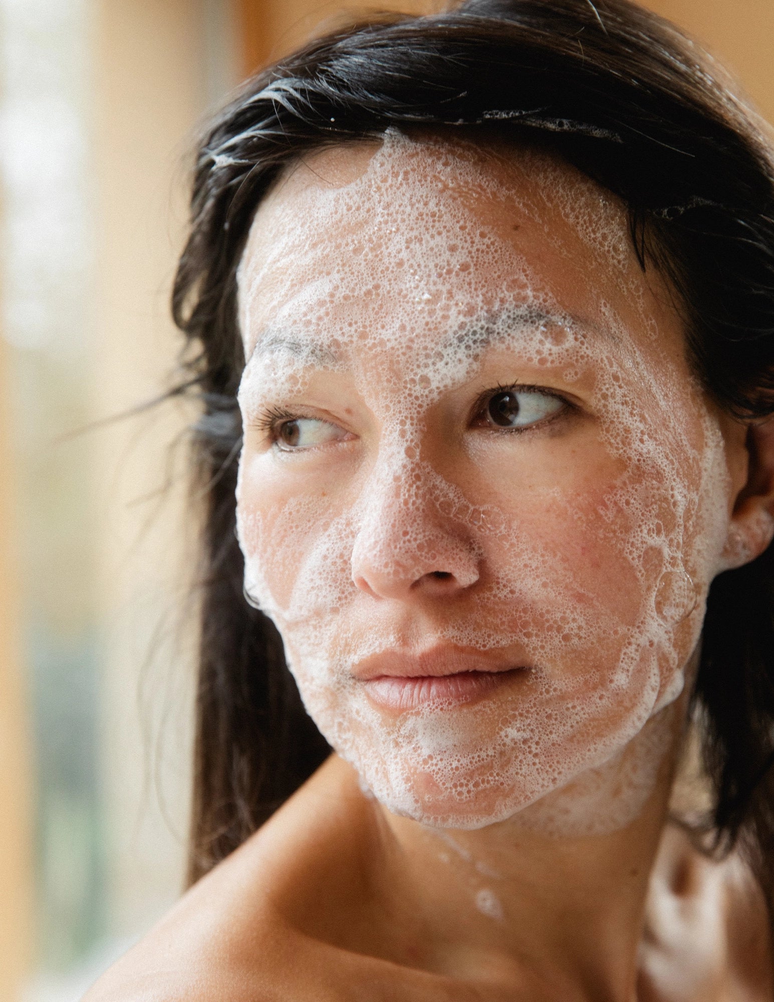 Woman with foaming face wash on her face