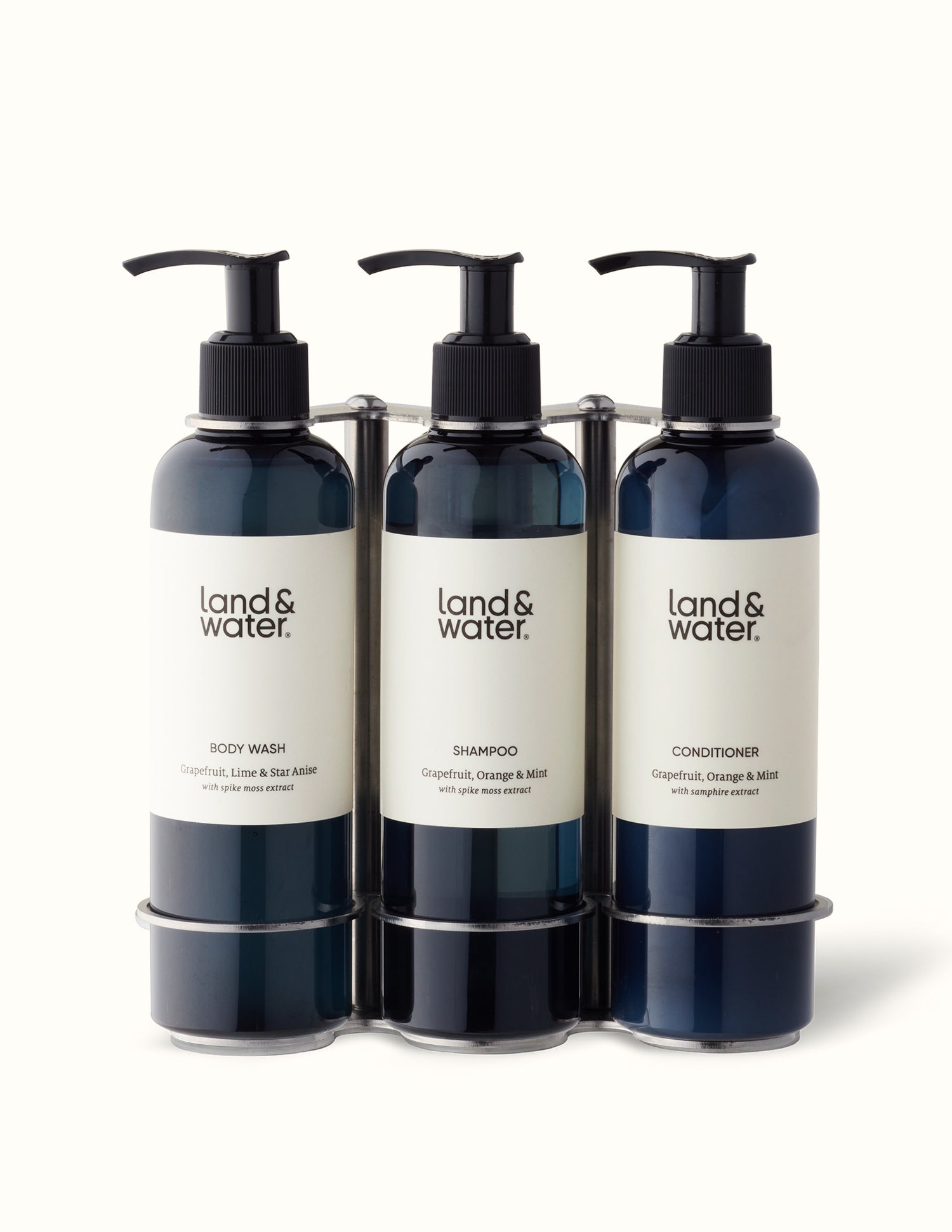 A brushed stainless steel triple wall bracket with three black pump bottles labeled &
