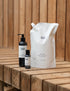 1 litre body wash refill pouch, 250ml body wash bottle, 50ml body wash bottle on wooden bench