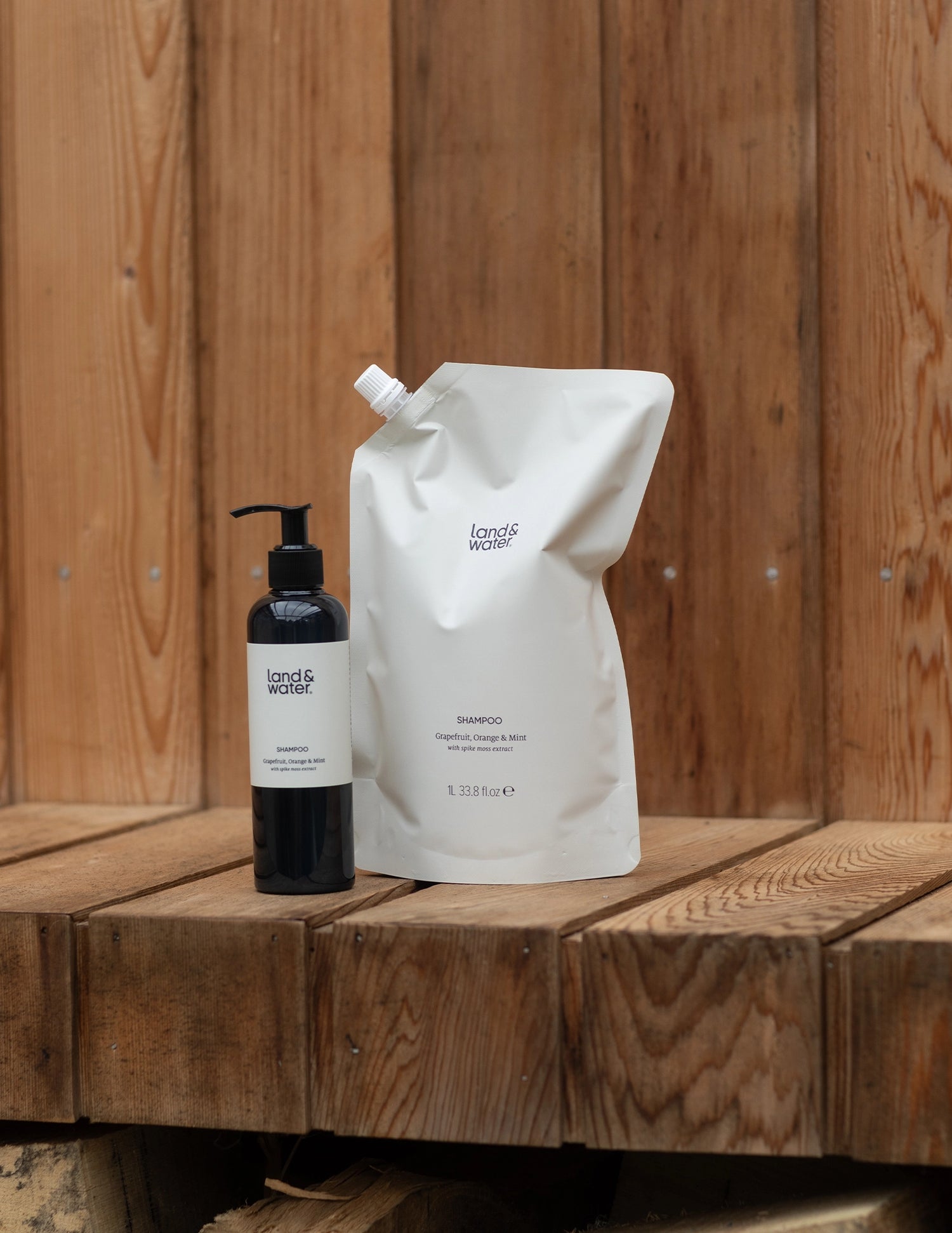 1 litre shampoo refill pouch and 250ml shampoo bottle on wooden shelf