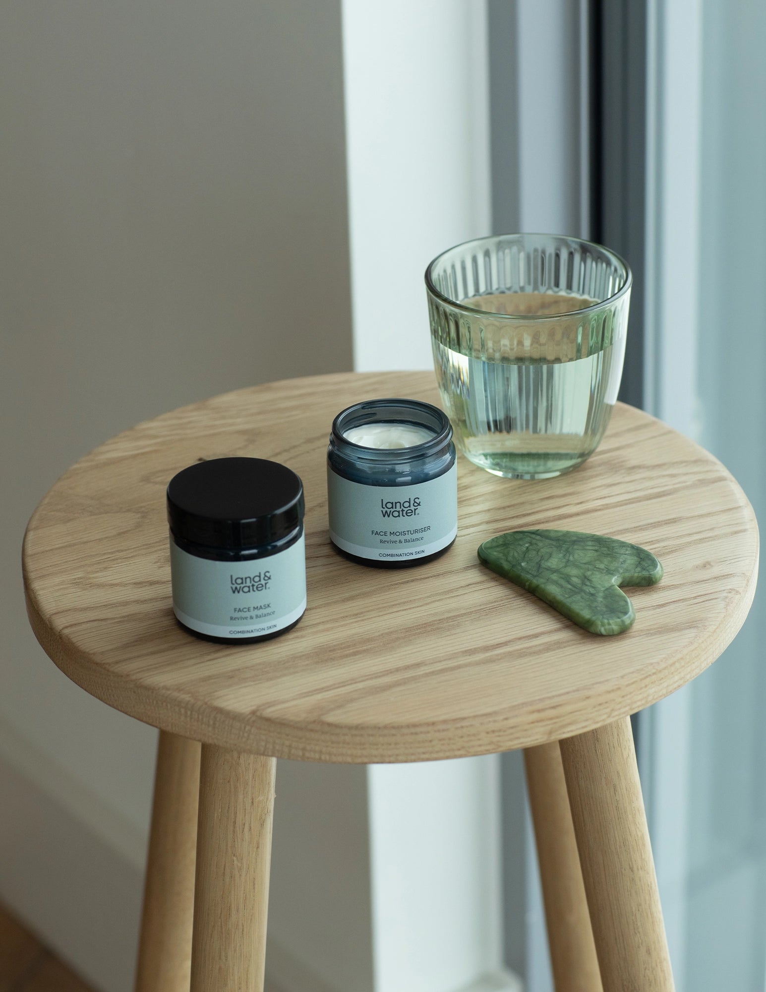 Face Moisturiser on a wooden stool with Face Mask product and glass of water