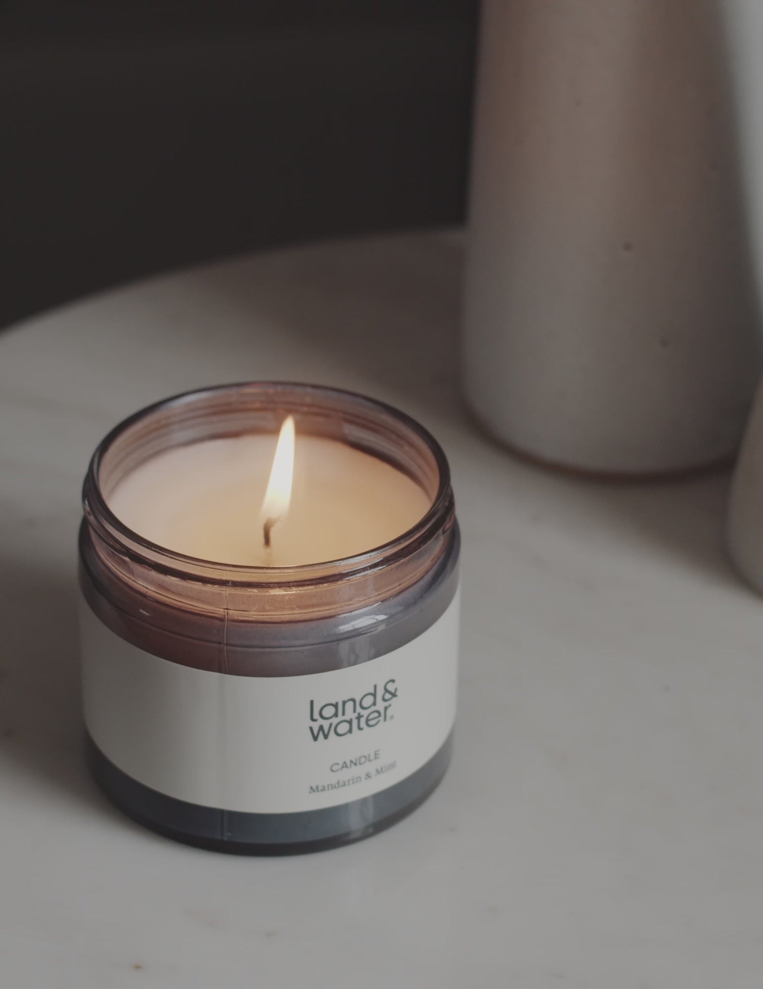 A flickering candle on a side table next to a woman reading a book.