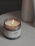 A flickering candle on a side table next to a woman reading a book.