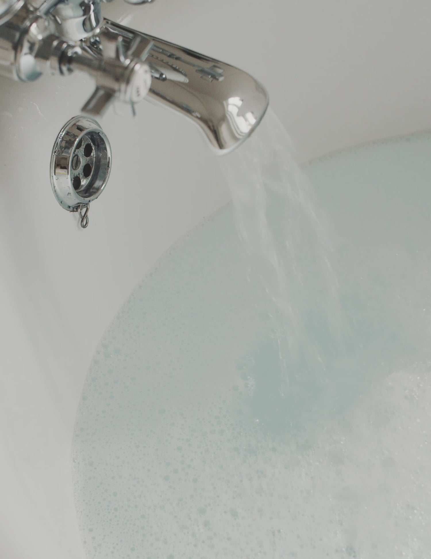 A short film clip of a tab running into a bath and a woman lathering body wash into foam in her hands and washing her arm, placing the body wash bottle on a shelf.