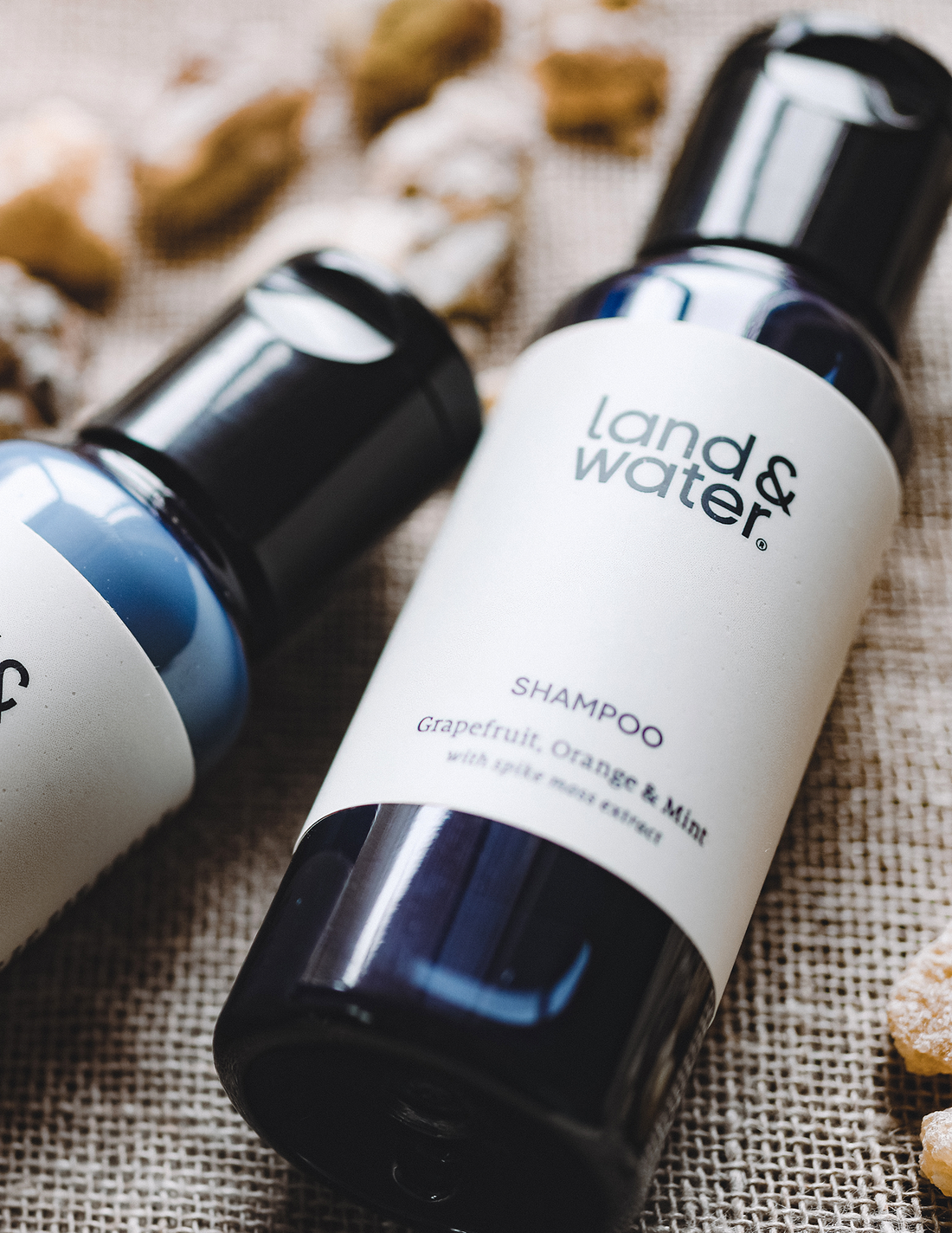mini shampoo (50ml) lying on hessian mat alongside another 50ml land&water product