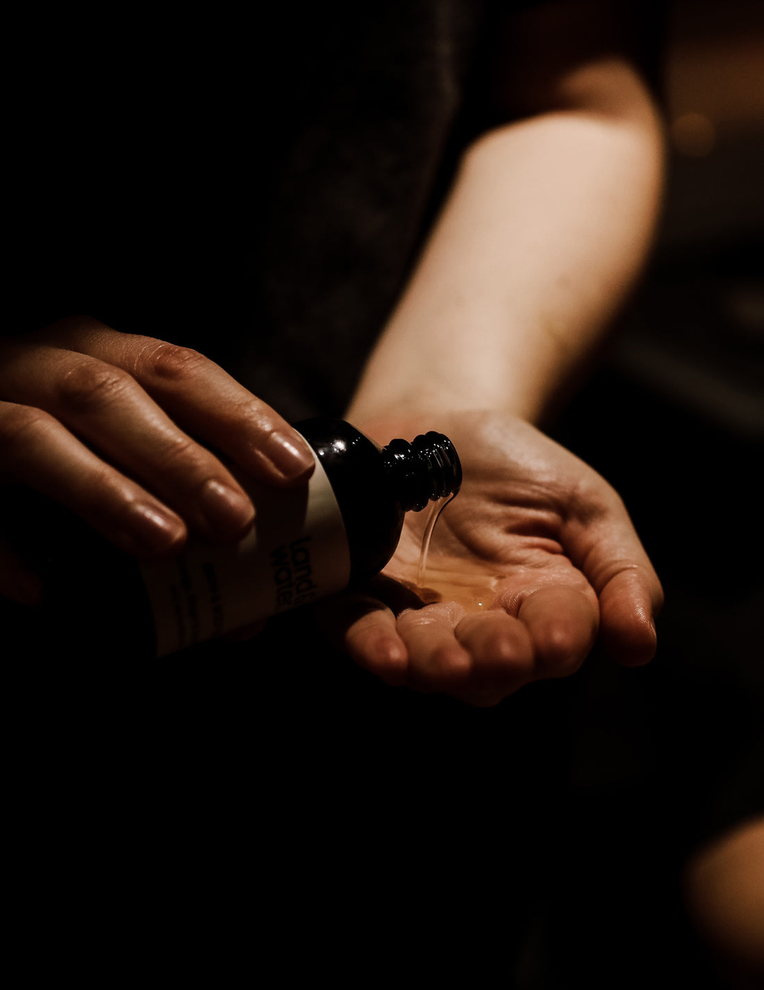 A person pouring some land&water Bath & Body Oil onto their hand