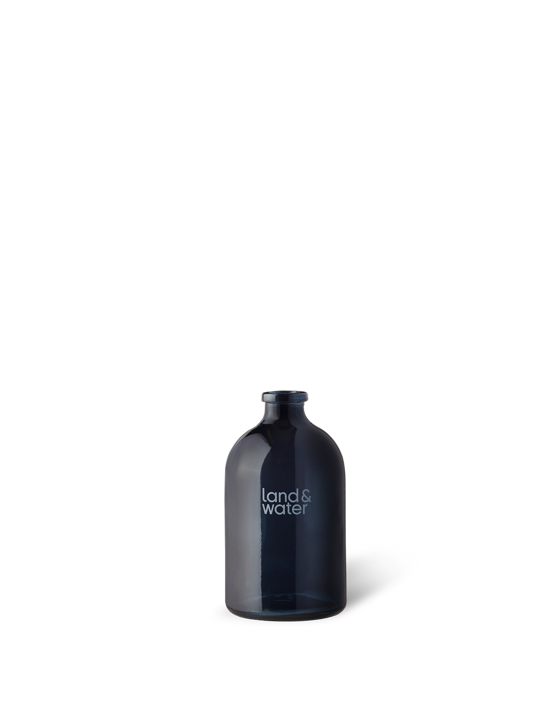 A navy blue glass diffuser vessel with a white label that reads &