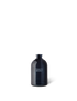 A navy blue glass diffuser vessel with a white label that reads &