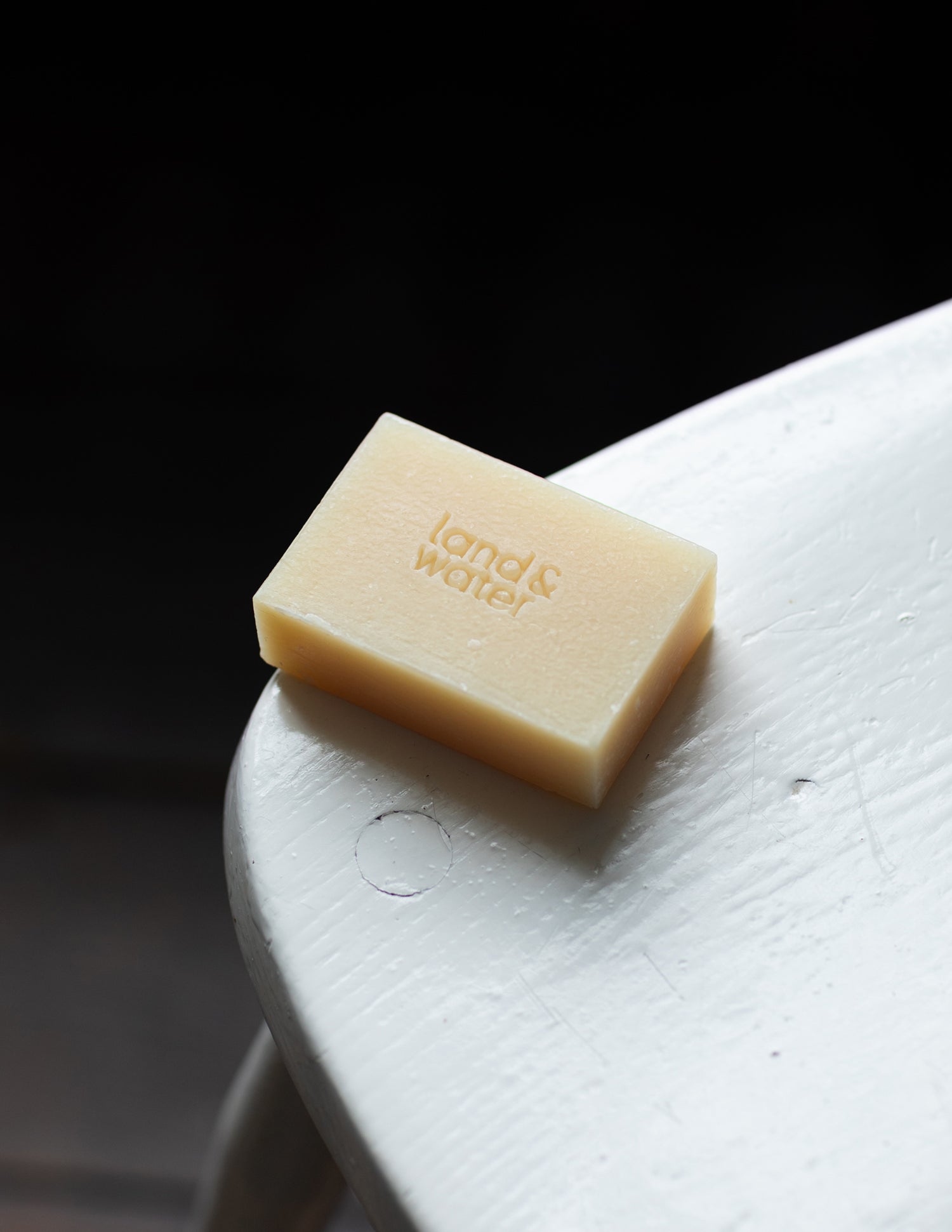 soap bar 100g embossed with land&water logo on a wooden chair