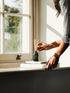 A person putting the reeds into a land&water reed diffuser on a windowsill