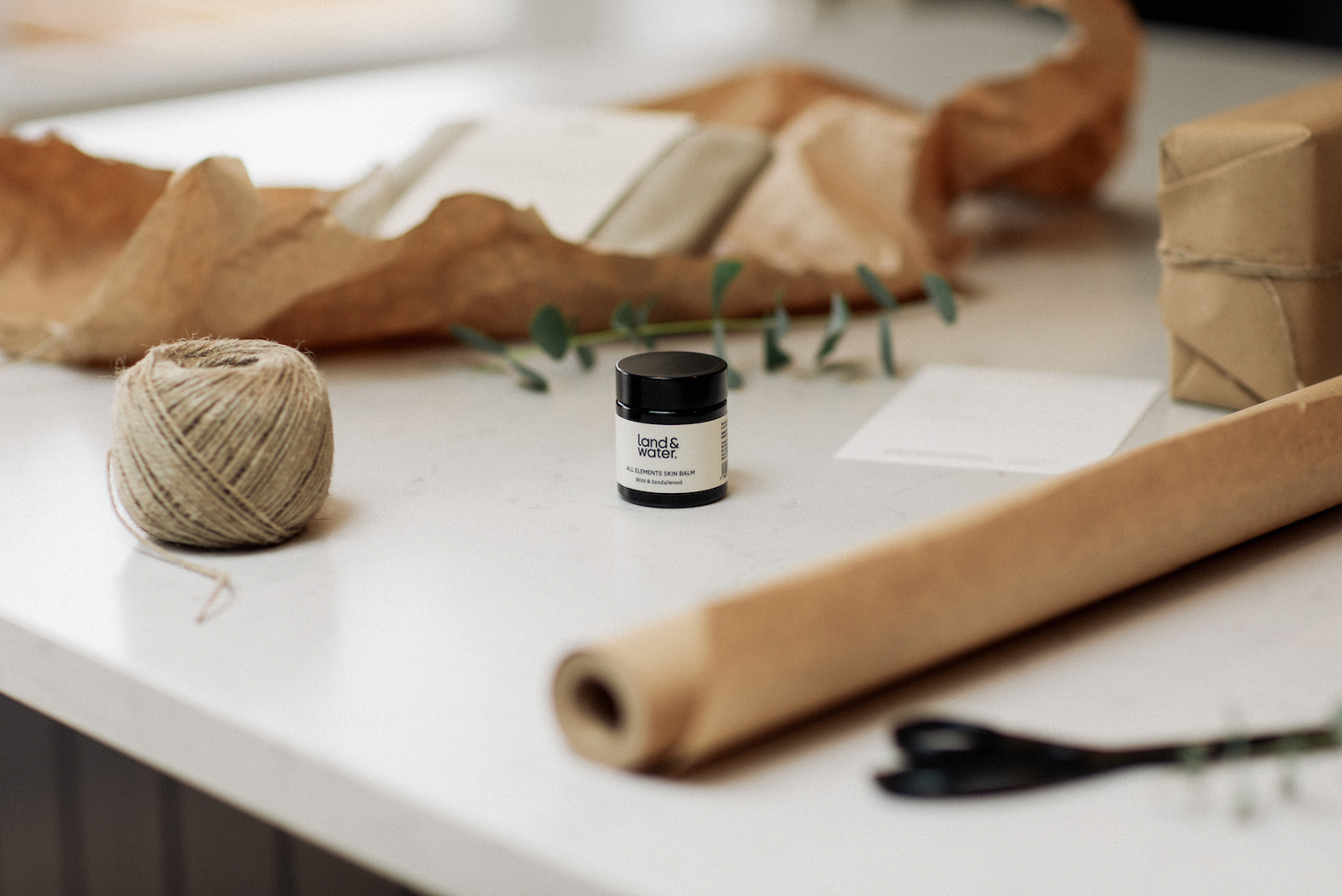 Wrapping table with land&water product ready to wrap (pictured with brown paper, string, scissors and eucalyptus)