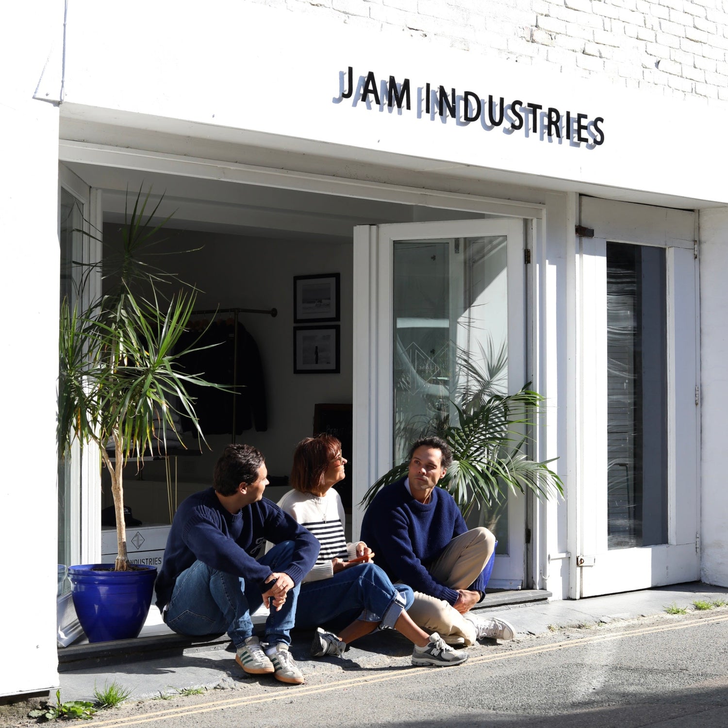 People sitting outside a building with 'JAM INDUSTRIES' sign