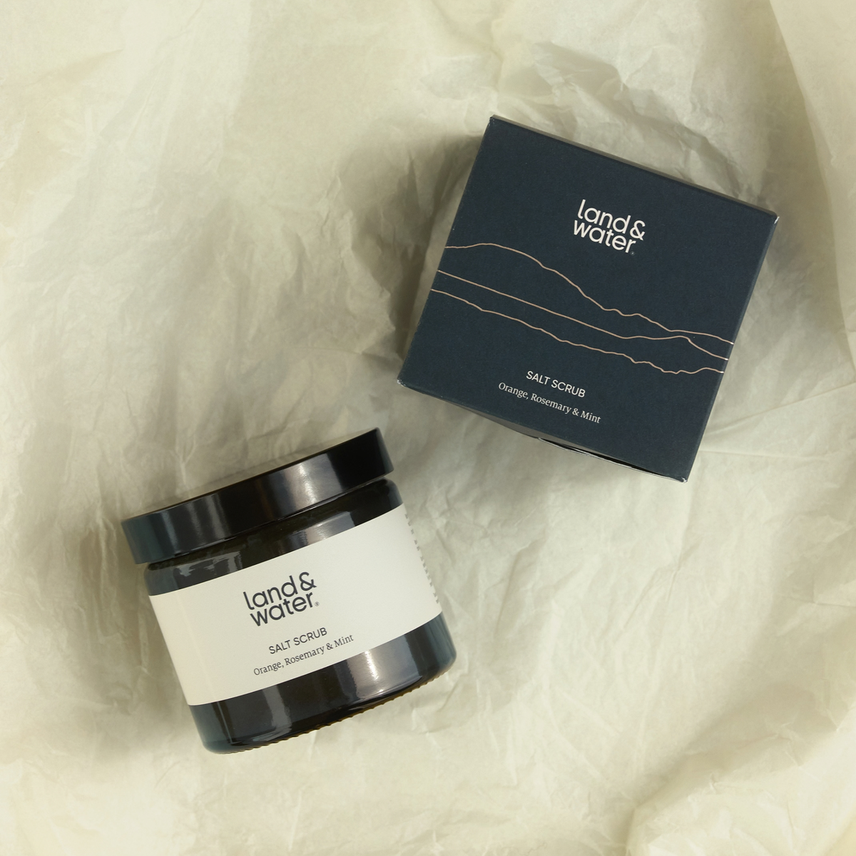 Salt scrub in jar with gift box next to it, on tissue paper for gifting