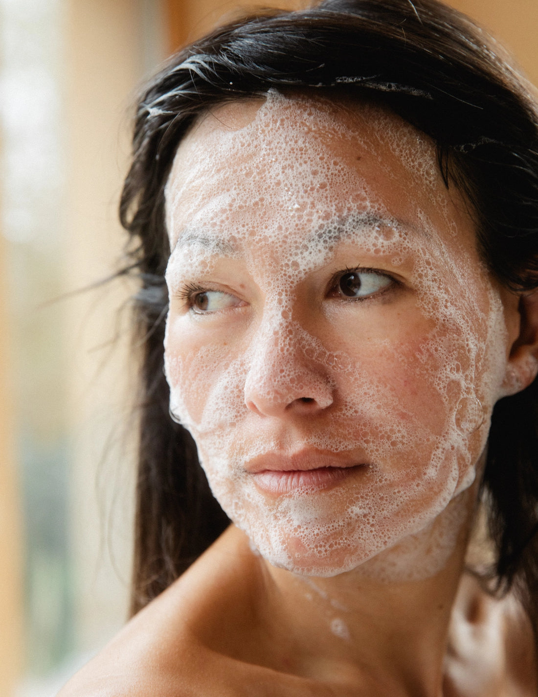 Woman with foaming face wash on her face