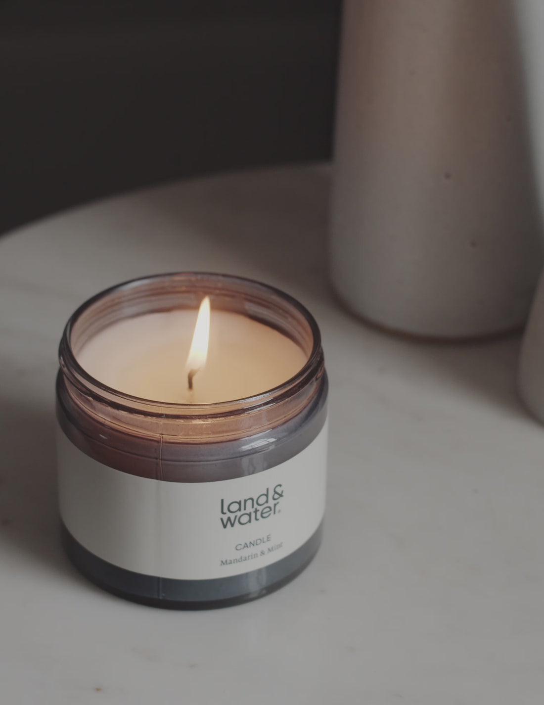 A flickering candle on a side table next to a woman reading a book.